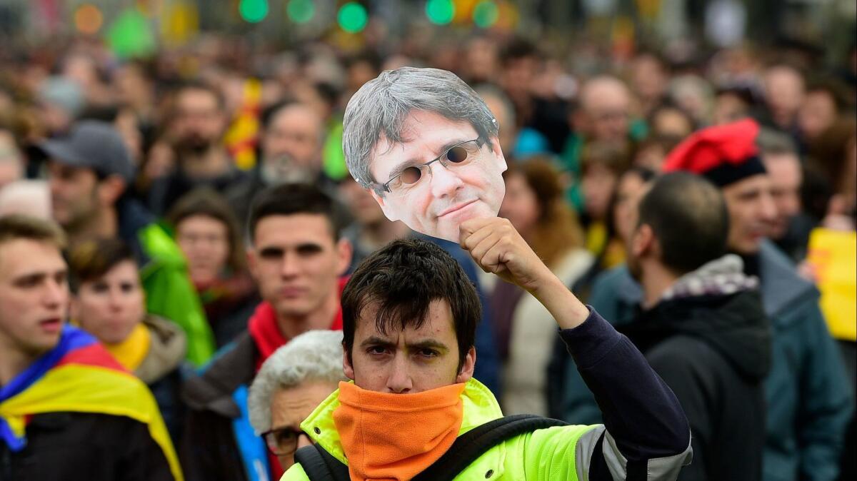 A protester holds a mask of Catalonia's former president, Carles Puigdemont, during a demonstration in Barcelona on Sunday.
