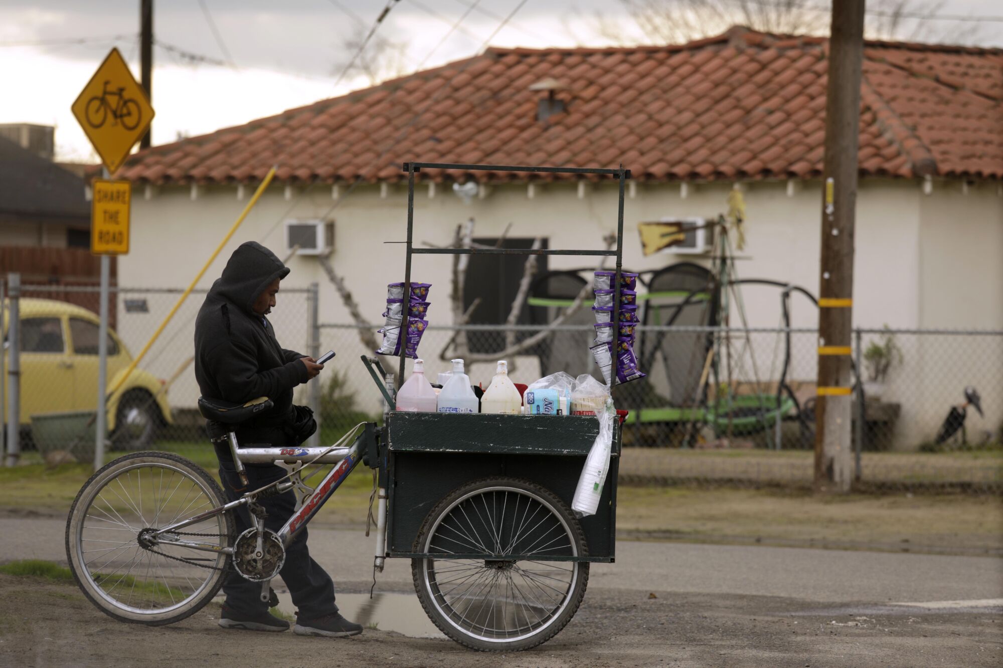 A man pauses by a cart selling aguas frescas.