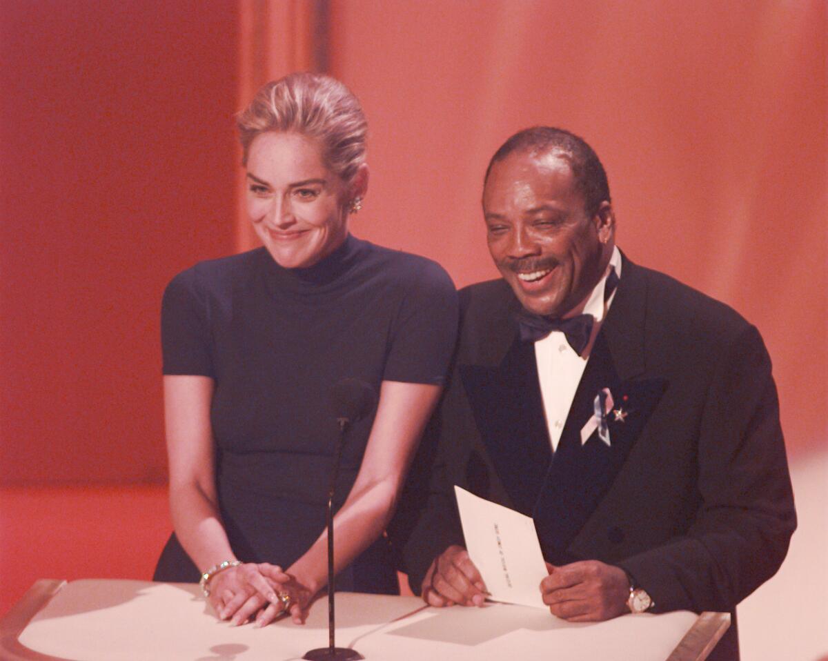 Sharon Stone, left, in a black Gap T-shirt, on stage with Quincy Jones at the 1996 Academy Awards.
