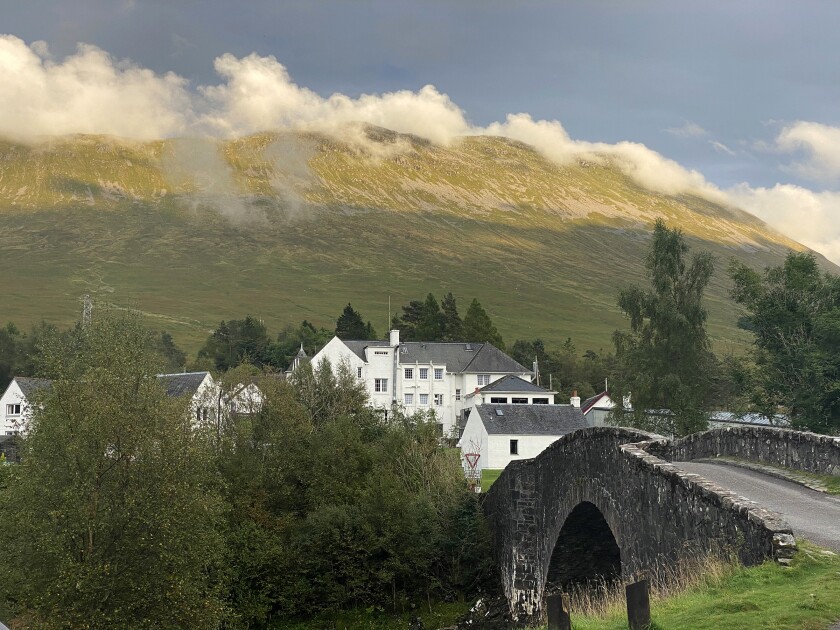 A bridge with a hotel in the background in the Scottish Highlands.