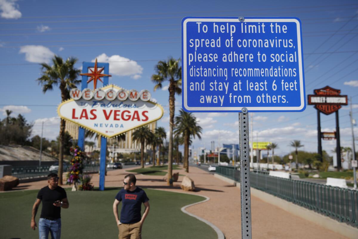  "Welcome to Fabulous Las Vegas Nevada" sign is paired with a sign about social distancing in the time of coronavirus. 