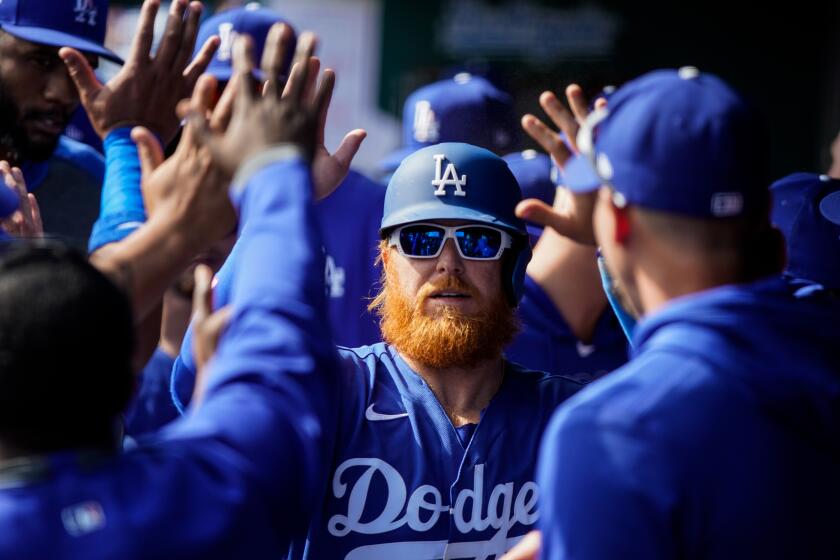 PHOENIX, ARIZ. - FEBRUARY 23: Los Angeles Dodgers Justin Turner (10) celebrates in the dugout with teammates after scoring against the Chicago Cubs during a Spring Training game at Camelback Ranch on Sunday, Feb. 23, 2020 in Phoenix, Ariz. (Kent Nishimura / Los Angeles Times)