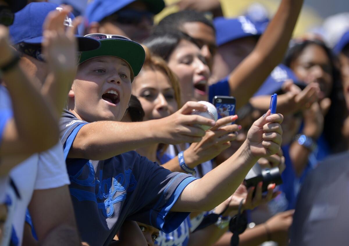 Dodgers fans try to get autographs from players before a game against the Colorado Rockies in July.