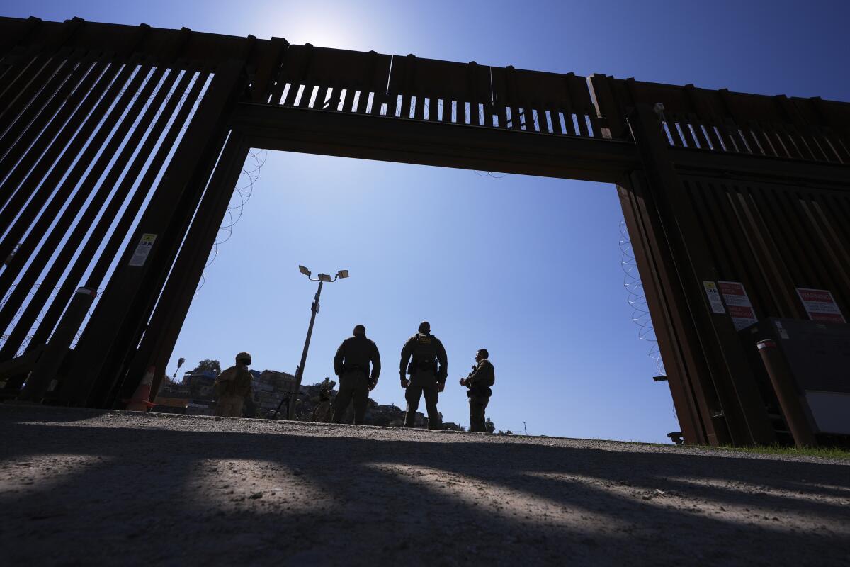 Border Patrol agents stand inside a gate in one of two border walls separating Mexico from the United States.