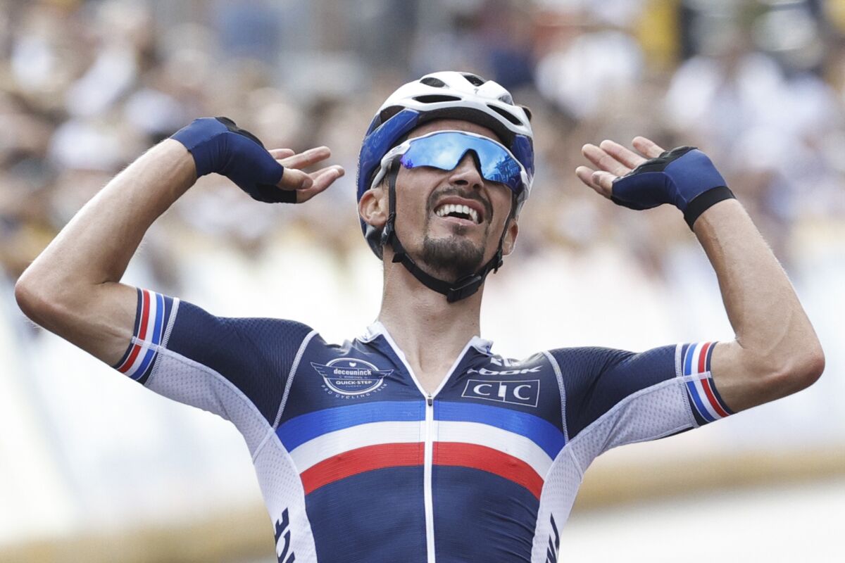 Last year's world champion Julian Alaphilippe of France celebrates crosses the finish line to claim his second title and win the men's road race of the World Road Cycling Championships with finish in Leuven, Belgium, Sunday, Sept. 26, 2021. (AP Photo/Olivier Matthys)
