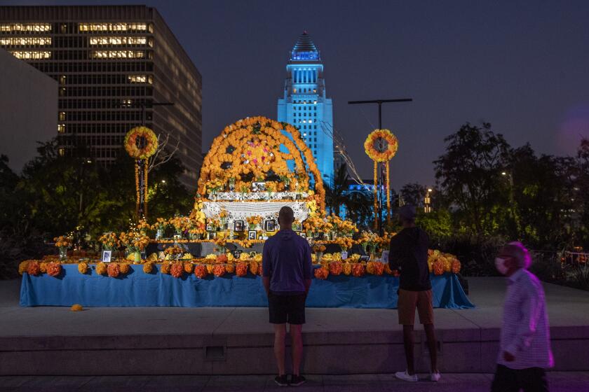 LOS ANGELES, CA -OCTOBER 28, 2020:People observe the community altar at Grand Park in downtown Los Angeles. The altar, designed by Ofelia Esparza and Rosanna Esparza, is for Covid-19 victims. Altars are popping up across L.A. for the lives lost to the coronavirus. (Mel Melcon / Los Angeles Times)
