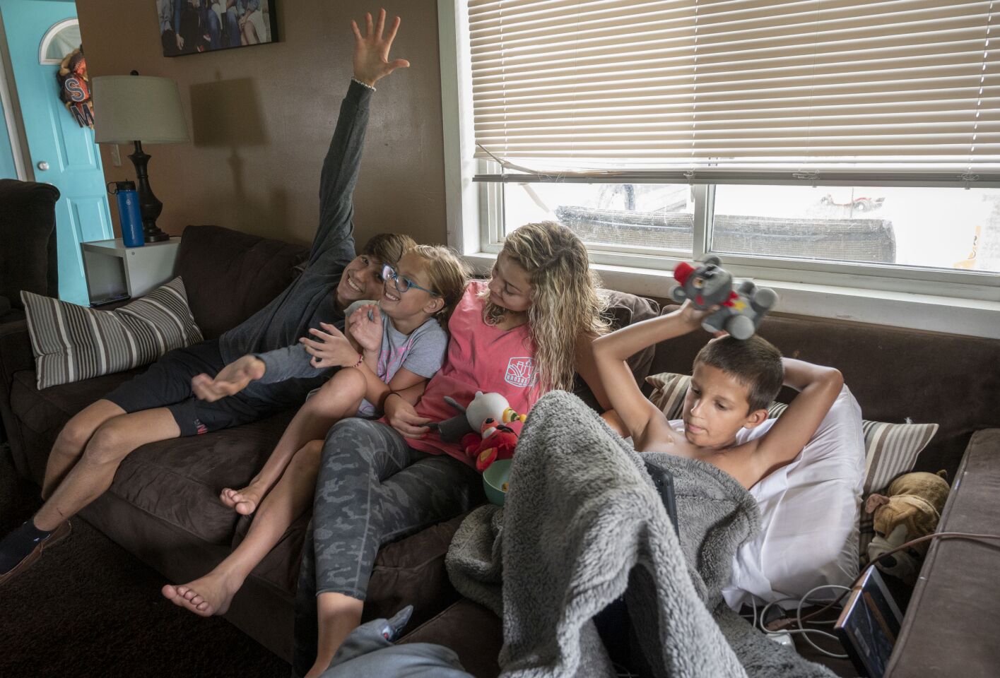 Siblings Johnny, 16; Brooklynn, 9; and Leksi, 18, crowd onto the couch with Bo as he rests.