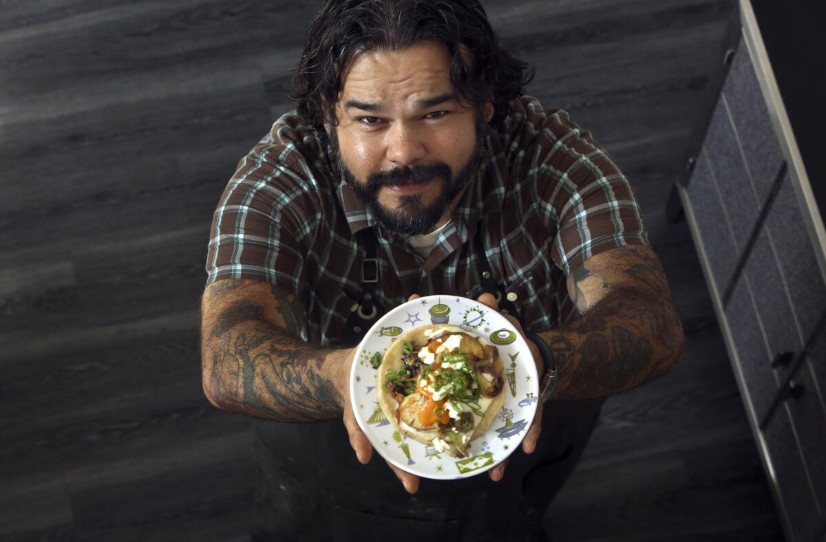 Wes Avila of Guerrilla Tacos holds up his sweet potato breakfast taco, that he made at his home in Glendale.