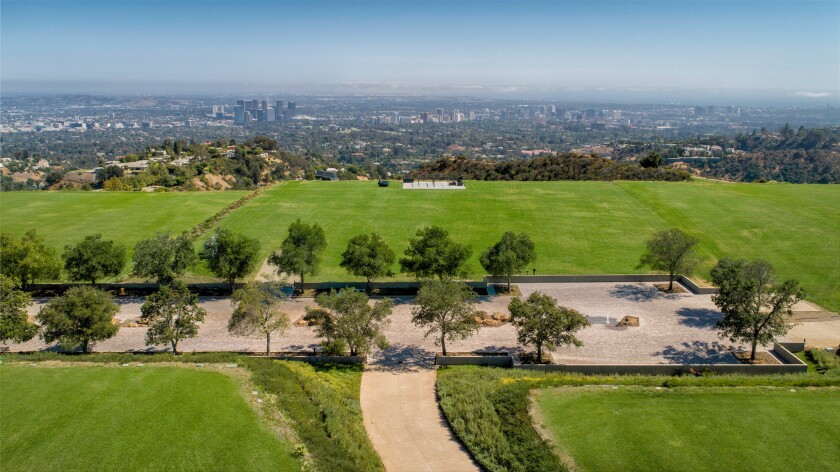 Aerial view of green grass and trees on a hilltop parcel of undeveloped land overlooking the Los Angeles Basin