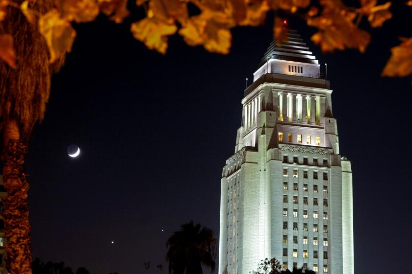 LOS ANGELES, CA. DECEMBER 1, 2008. A rare celestial conjunction of the waxing crescent moon, Venus and Saturn shine in the southern sky behind Los Angeles City Hall.