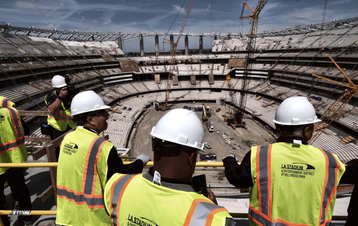 Miembros de los medios de comunicación realizan un paseo en el nuevo estadio de la NFL en Los Ángeles mientras sigue en construcción durante una ceremonia de colado en Inglewood, California.