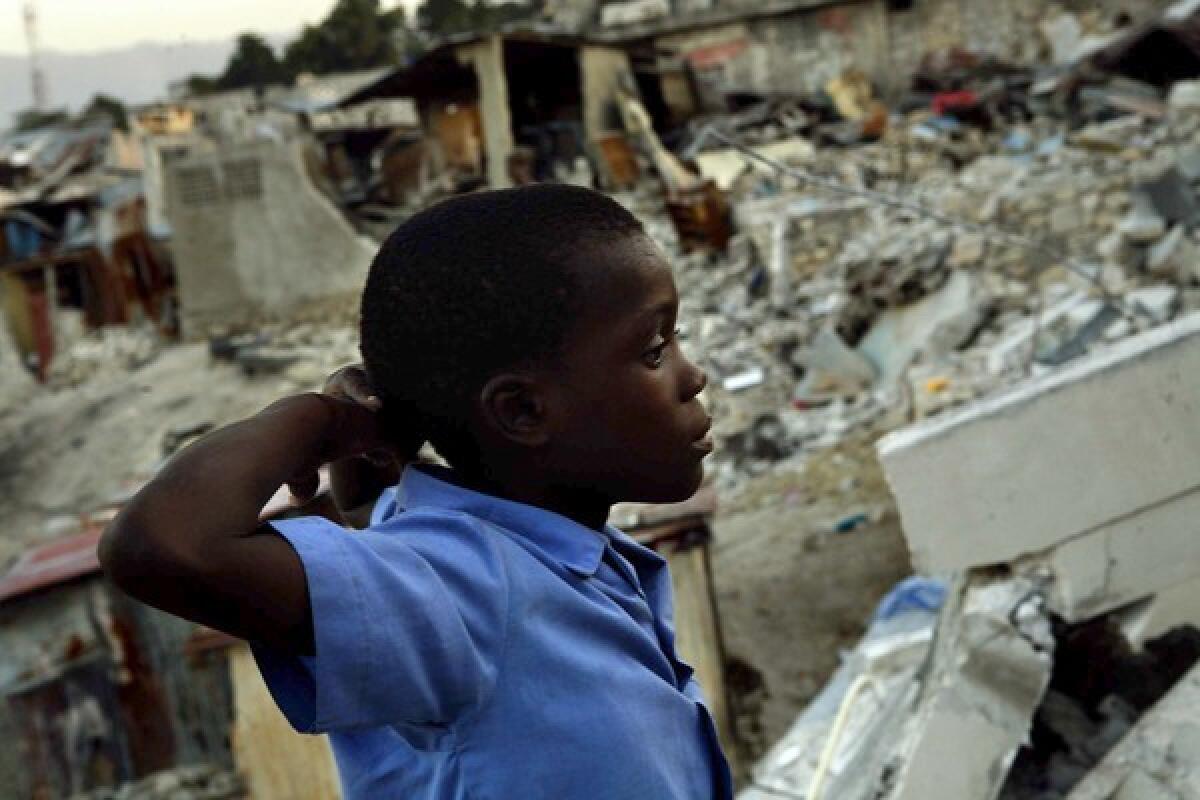 Clifford Berrette, 11, stands next to the rubble of his neighbor's home. He and his mother lived in a metal shack below, where his 2-year-old sister died in the earthquake. Audio slide show: A kokorat on the streets of Port-au-Prince.