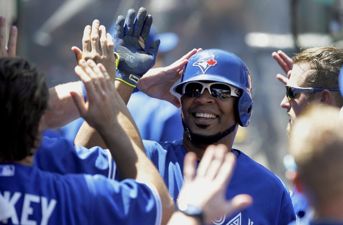 Blue Jays designated hitter Edwin Encarnacion is congratulated by teammates after scoring against the Angels on an infield single by Ben Revere in the third inning Sunday.