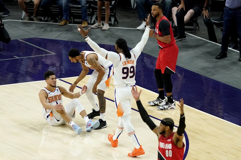 Phoenix Suns guard Devin Booker is helped up by guard Cameron Payne as forward Jae Crowder (99) cheers after being fouled in the final seconds during the second half of an NBA basketball game against the Portland Trail Blazers, Thursday, May 13, 2021, in Phoenix. (AP Photo/Matt York)