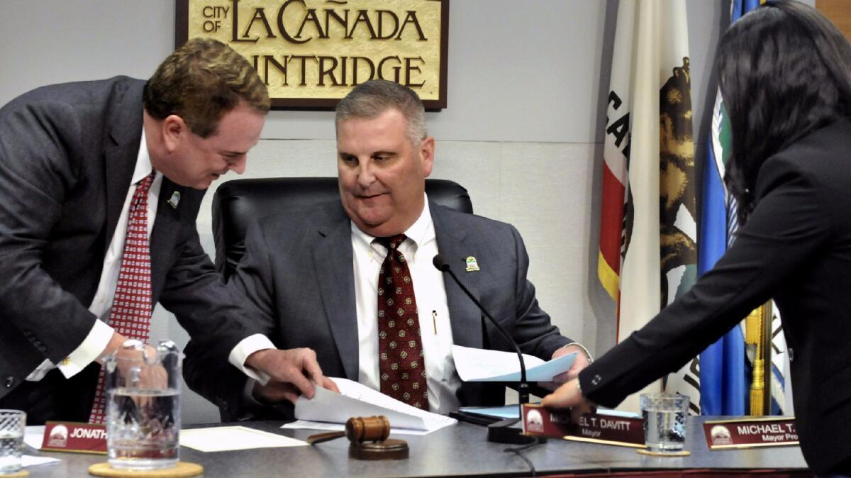 Outgoing Mayor Jon Curtis, left, helps newly-appointed Mayor Mike Davitt into his seat.