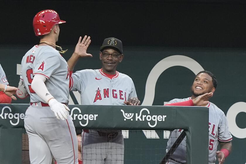 Los Angeles Angels' Zach Neto (9) is congratulated at the dugout by manager Ron Washington, center, and teammate Willie Calhoun (5) after hitting a home run that also scored teammate Jo Adell during the fourth inning of a baseball game against the Texas Rangers in Arlington, Texas, Friday, May 17, 2024. (AP Photo/LM Otero)