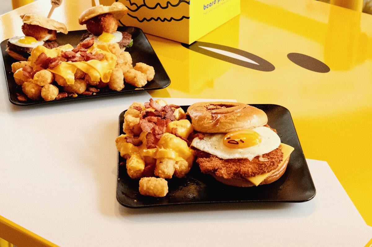 An egg-topped katsu sandwich and egg-topped sliders both with tots on a Gudetama table at the Gudetama Cafe in Buena Park