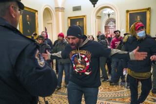 FILE - In this Jan. 6, 2021, file photo, Trump supporters, including Doug Jensen, center, confront U.S. Capitol Police in the hallway outside of the Senate chamber at the Capitol in Washington. Some followers of the QAnon conspiracy theory are now turning to online support groups and even therapy to help them move on, now that it's clear Donald Trump's presidency is over. (AP Photo/Manuel Balce Ceneta, File)