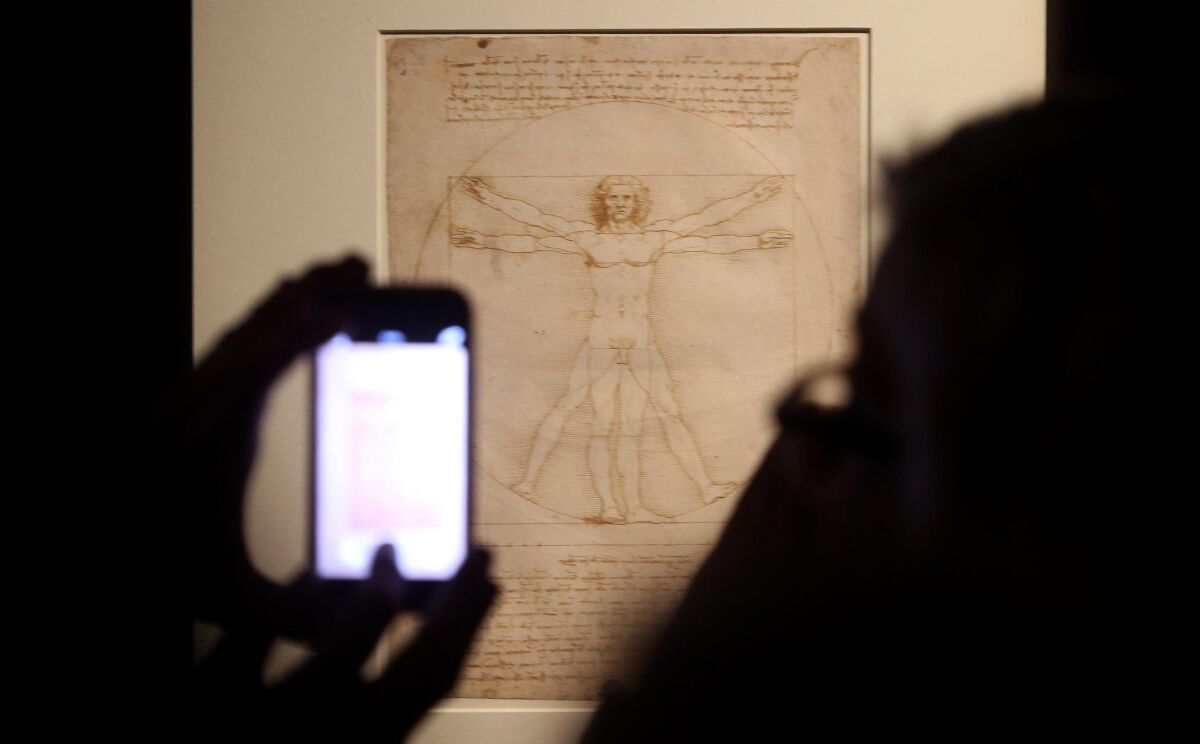 Museum visitors in Milan in 2019 visit Leonardo da Vinci's "Vitruvian Man" sketch from his notebooks.  