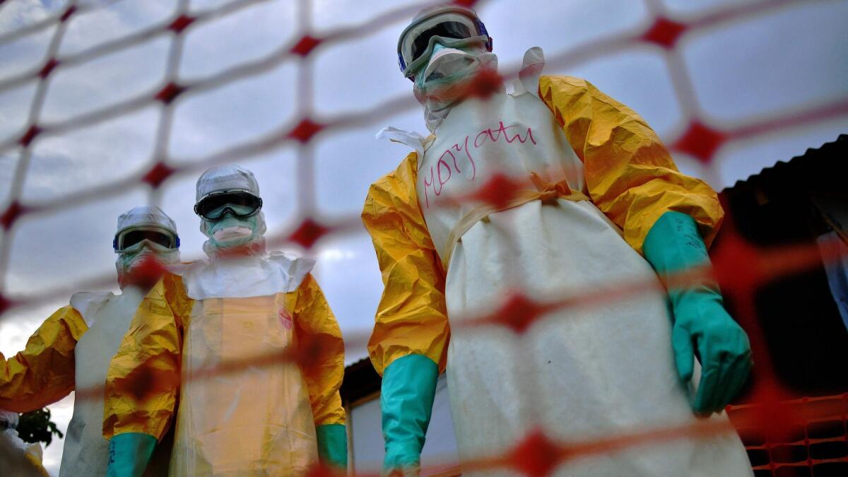 Doctors Without Borders staffers wear protective clothing to treat the body of an Ebola victim in Sierra Leone. Researchers have identified new mutations in the Ebola virus that helped it infect more human victims in the recent outbreak.