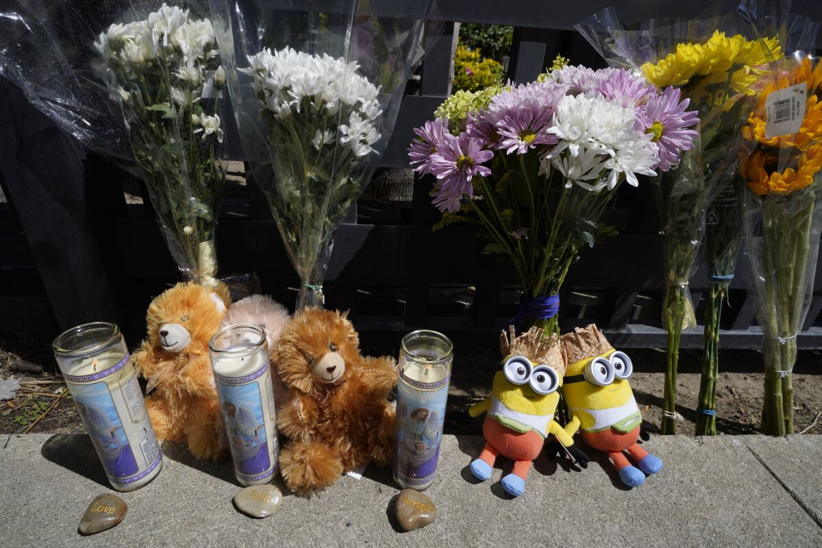 Flowers and teddy bears are left outside a ranch-style house in the West Hills neighborhood of the San Fernando Valley in Los Angeles, Monday, May 9, 2022. Police say three children were found dead at the home over the weekend and their mother and a teenager were arrested in the killings. (AP Photo/Damian Dovarganes)