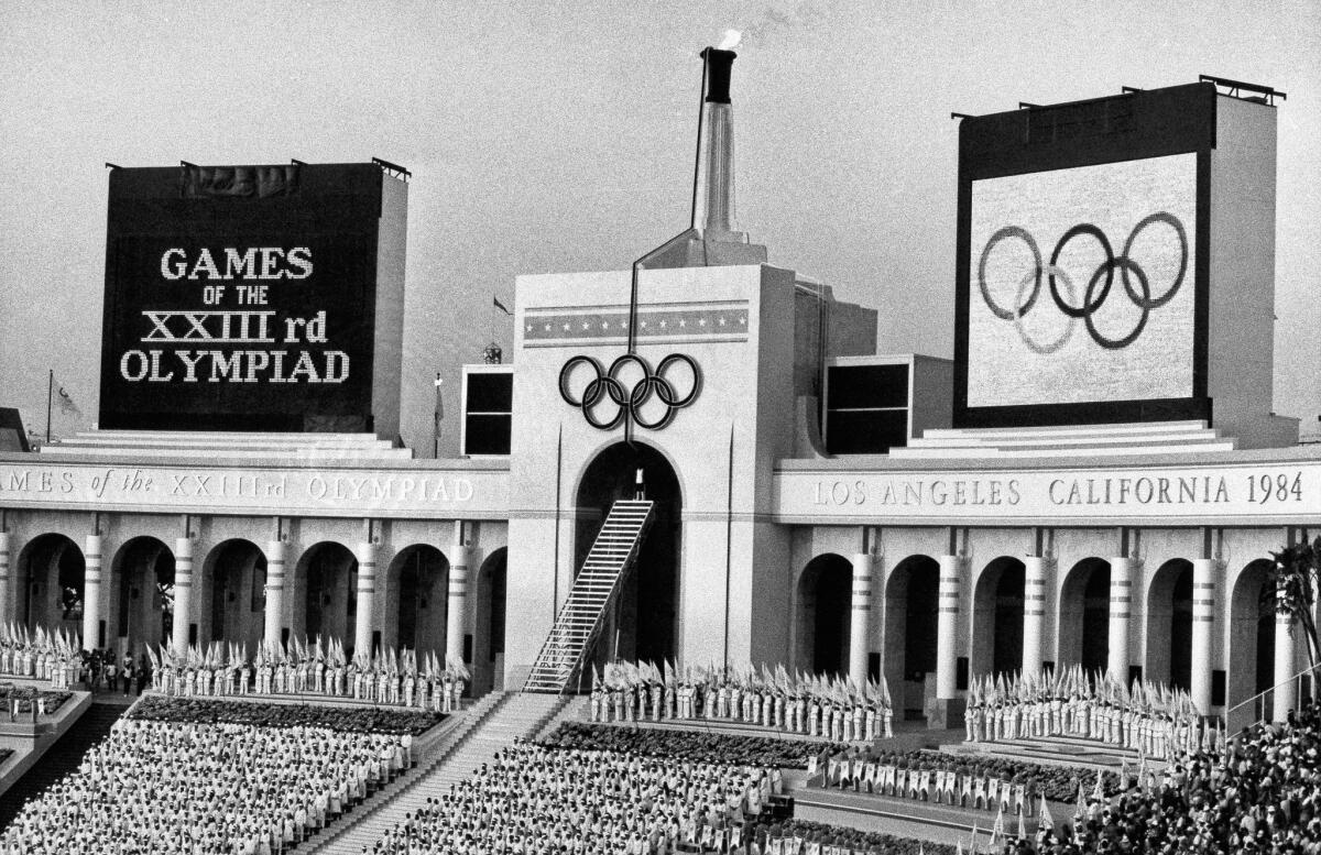In this July 28, 1984, photo, the Olympic flame is flanked by a scoreboard signifying the formal opening of the XXIII Olympiad after it was lighted by Rafer Johnson during the opening ceremonies in the Los Angeles Memorial Coliseum.