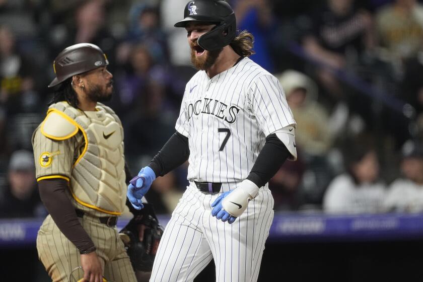 Colorado Rockies' Brendan Rodgers crosses home plate after hitting a grand slam, next to San Diego Padres catcher Luis Campusano during the fourth inning of a baseball game Tuesday, April 23, 2024, in Denver. (AP Photo/David Zalubowski)