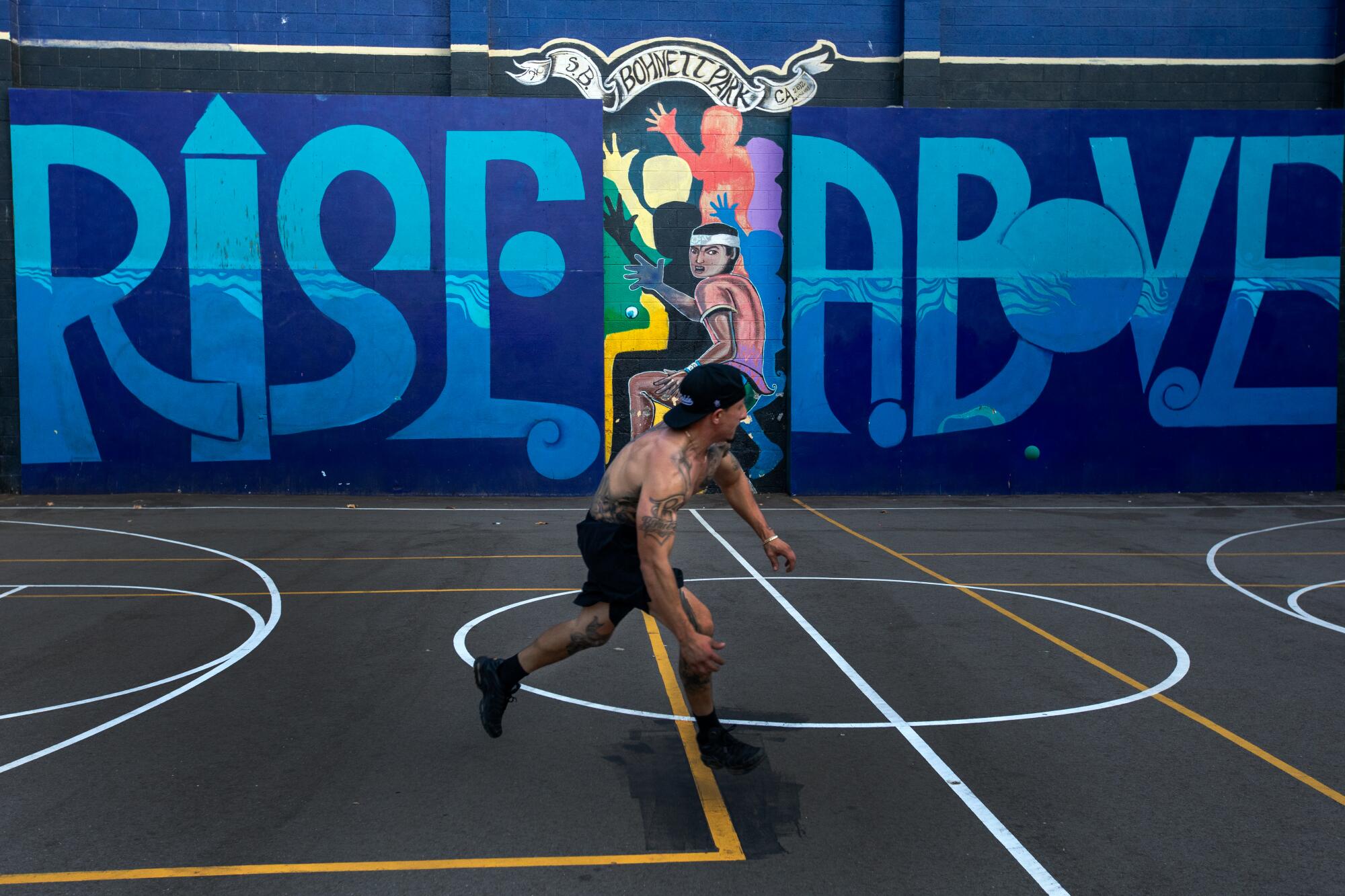Adrian Campos plays handball in Bonhett Park against a mural in Santa Barbara's Westside 