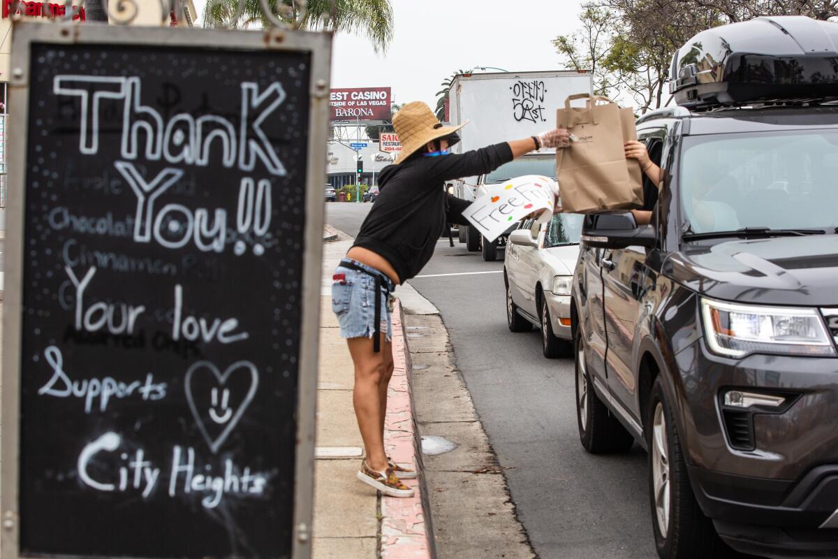 Marcela Talavera gives free bags of fruit to passing vehicles on El Cajon Boulevard in City Heights on Wednesday.