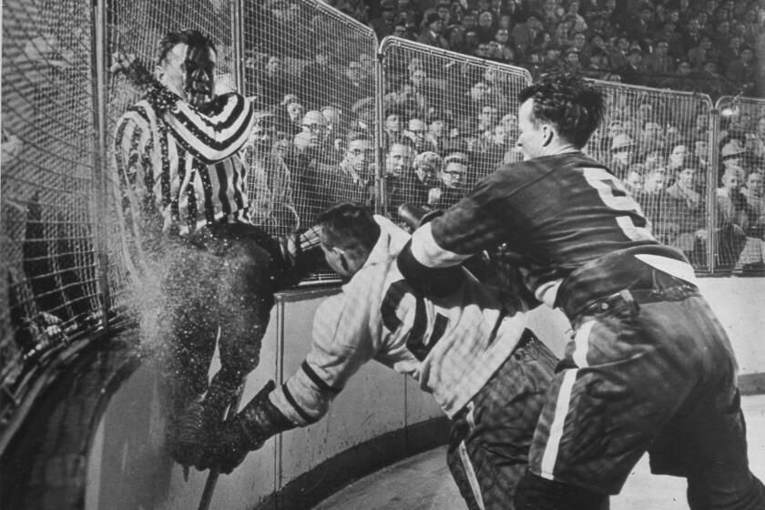 Detroit Red Wings star Gordie Howe (9) checks a Chicago Blackhawks player into the boards during an NHL game in Detroit in the mid-1950s.