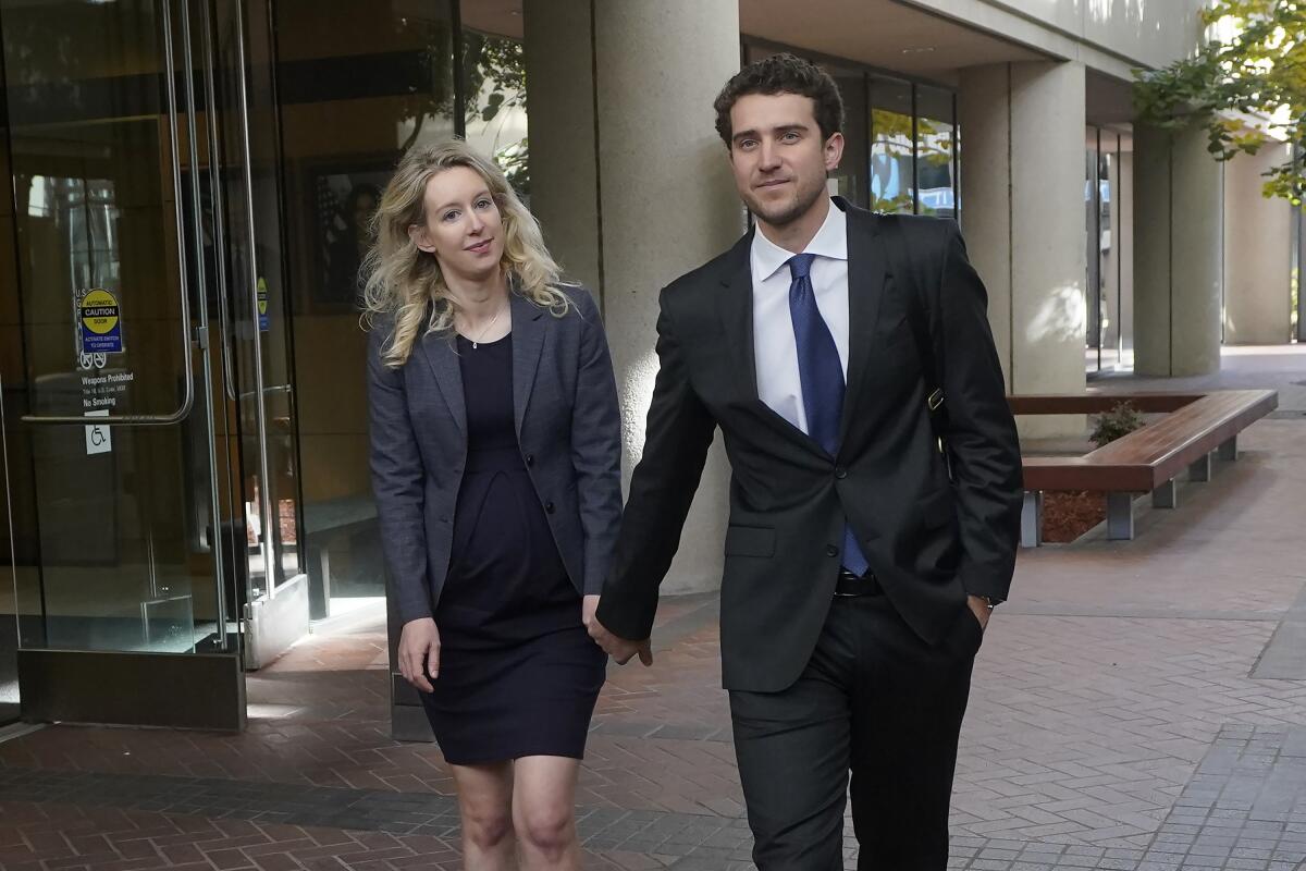 Former Theranos CEO Elizabeth Holmes, left, walks with her partner, Billy Evans, after leaving federal court in San Jose, Calif., Monday, Oct. 17, 2022. (AP Photo/Jeff Chiu)