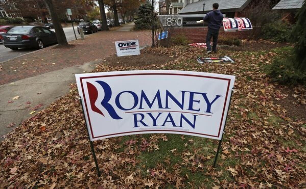 A campaign worker removes candidate signs from in front of Mitt Romney's campaign office in Manchester, N.H.