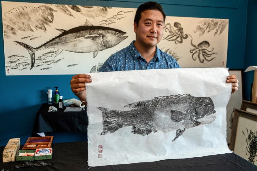 MISSION VIEJO, CA - THURSDAY, JUNE 29, 2023 - Dwight Hwang displaying a freshly made Sheephead gyotaku, June 29, 2023. Hwang, an artist based in Orange County, is popularizing the 19th-century Japanese art of gyotaku. Although obscure in the United States, gyotaku is commonplace in Japan, a form of taxidermy originally practiced by fishermen to commemorate their catches. His art captures the essence of the local seafood of a region and shares the Japanese cultural love and admiration for simple, fleeting pleasures like the catch of the day. (Ricardo DeAratanha/Los Angeles Times)