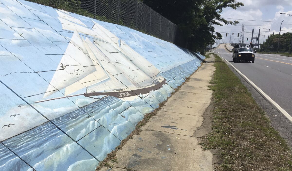 FILE - In this May 30, 2019, file photo, traffic passes a mural of the slave ship Clotilda along Africatown Blvd. in Mobile, Ala. The last slave ship known to have landed in the United States more than 150 years ago has a new owner: The state of Alabama. A federal judge granted ownership of the Clotilda shipwreck to the Alabama Historical Commission in a one-page order released Monday, April 13, 2020. (AP Photo/Kevin McGill, File)
