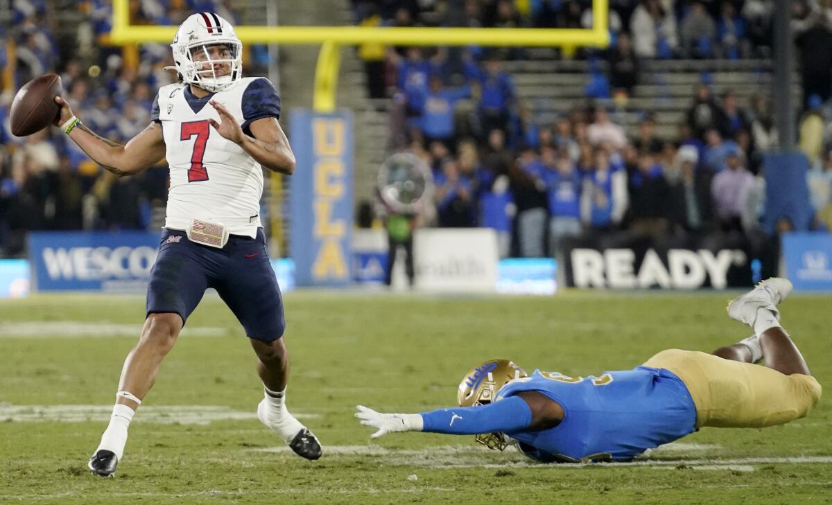 Arizona quarterback Jayden de Laura throws a touchdown pass as UCLA defensive lineman Jacob Sykes reaches for him.