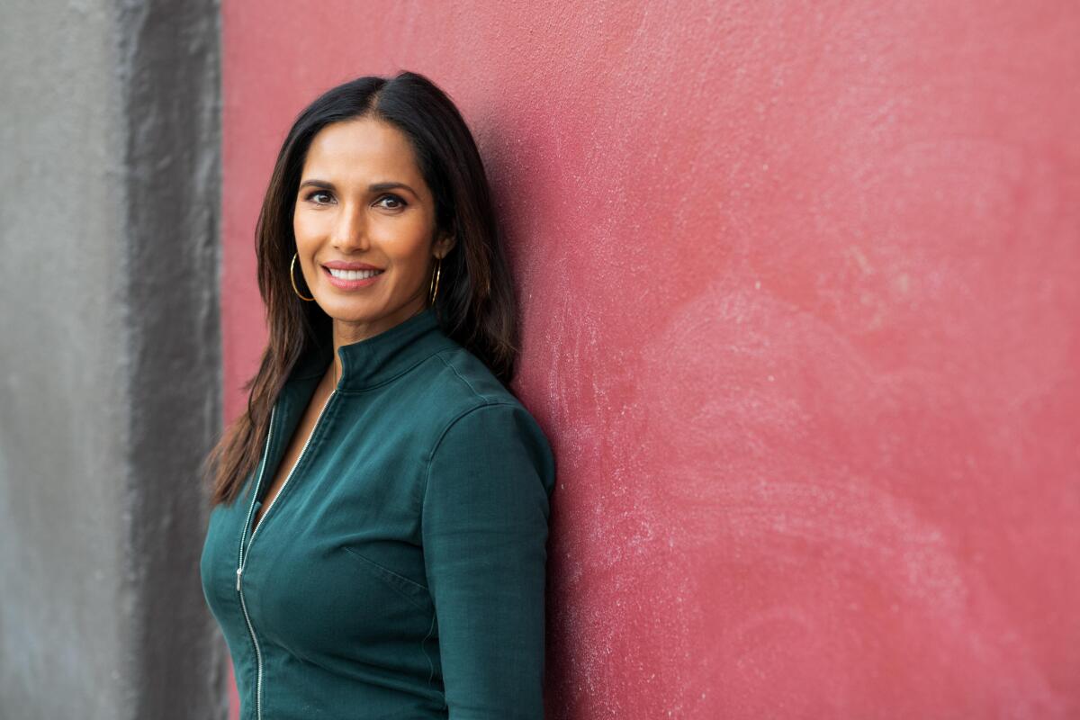 Padma Lakshmi leans against a colorful wall for a portrait.