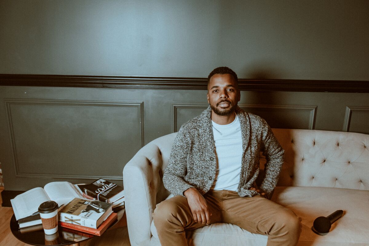 man in khakis and a cardigan on a beige couch
