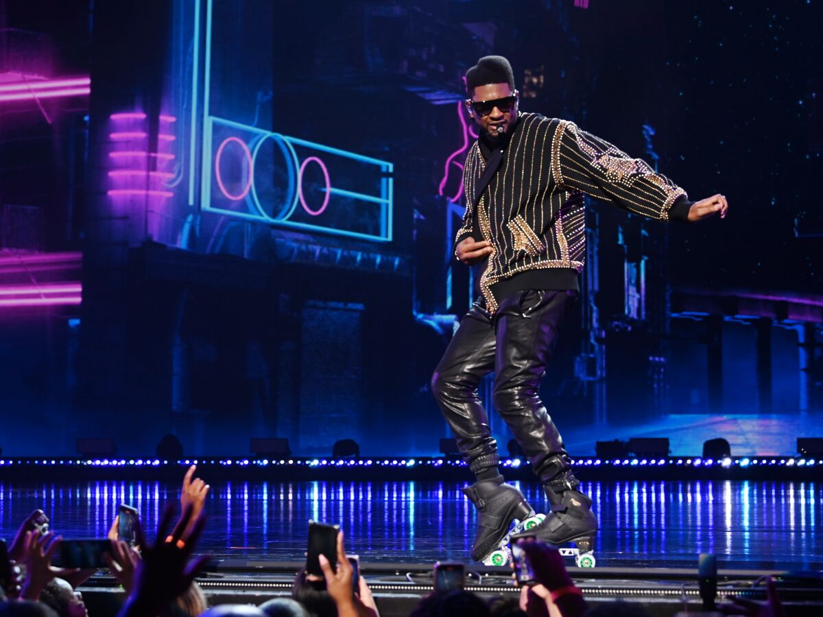A male singer in leather pants performs onstage.