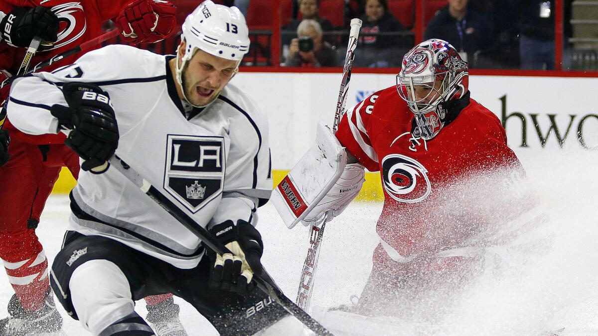 Kings forward Kyle Clifford, left, can't keep control of the puck in front of Carolina Hurricanes goalie Cam Ward during the first period of the Kings' 3-2 loss Sunday.