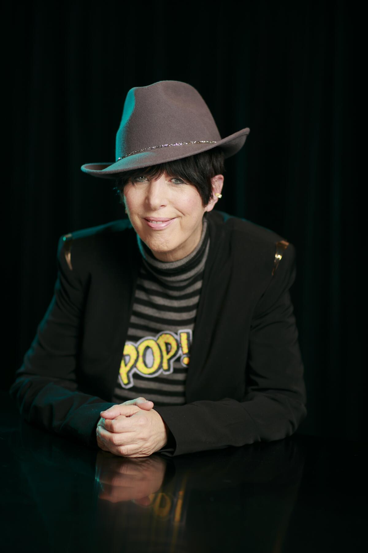Songwriter Diane Warren poses for a portrait in a hat and shirt that reads Pop!