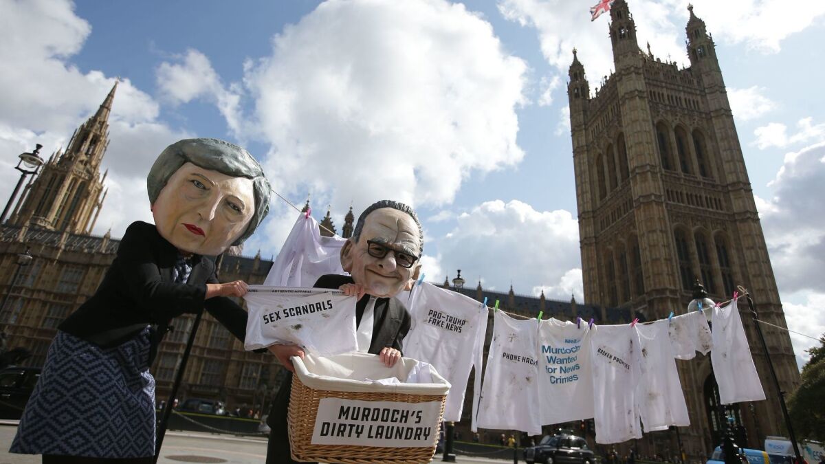 Activists from the organization Avaaz satirically posed as British Prime Minister Theresa May, left, and media mogul Rupert Murdoch last year to protest Fox's attempted consolidation of Sky, which runs the popular Sky News Channel.