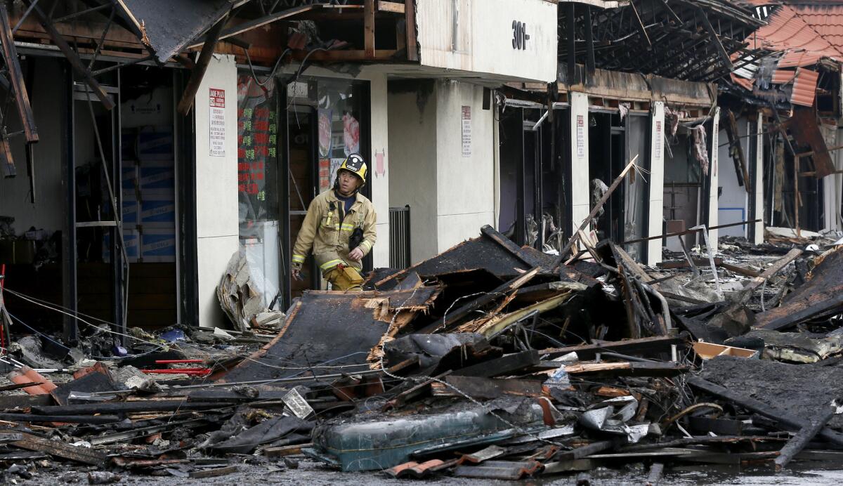 A Monterey Park firefighter looks for hot spots in the aftermath of a four-alarm fire at a Monterey Park strip mall Thursday.