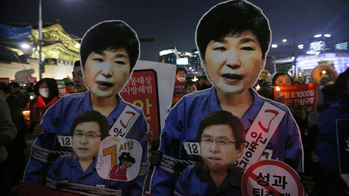 Protesters hold cutouts of impeached President Park Geun-hye, top, as they march toward the presidential house during a candlelight vigil in Seoul on Jan. 7, 2017.