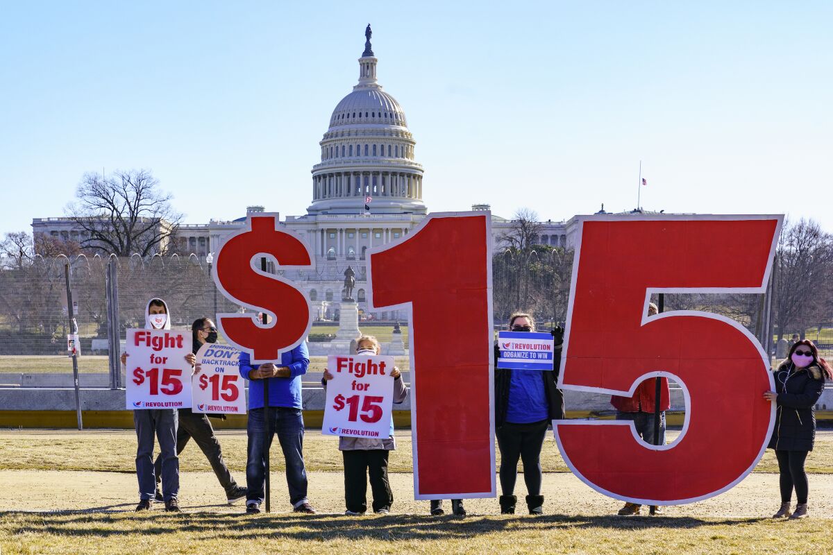 People hold signs in an appeal for a $15 minimum wage.