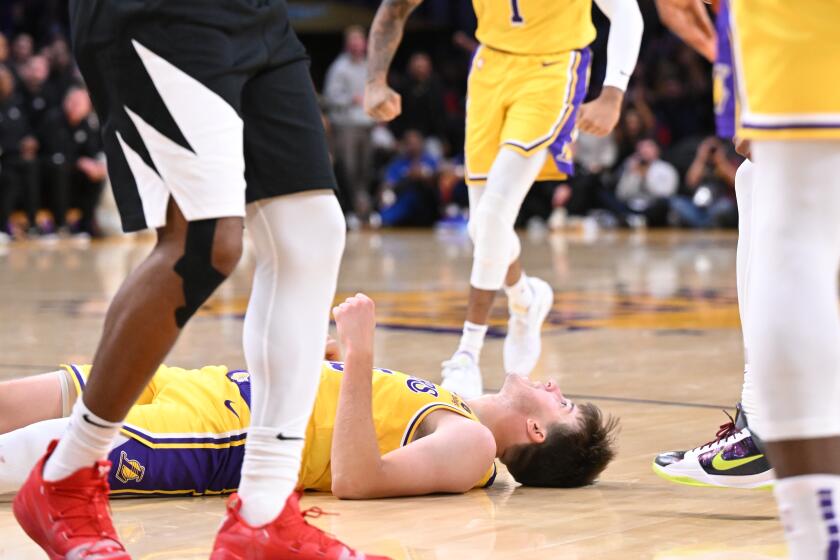 The Lakers' Austin Reaves, on the floor, celebrates his basket after being fouled by the Clippers' Norman Powell.