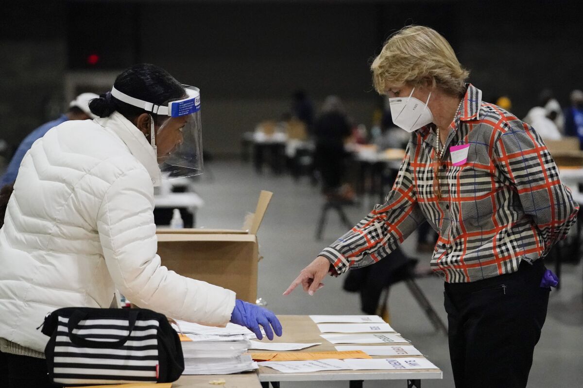 An election official helps another as they sort ballots.