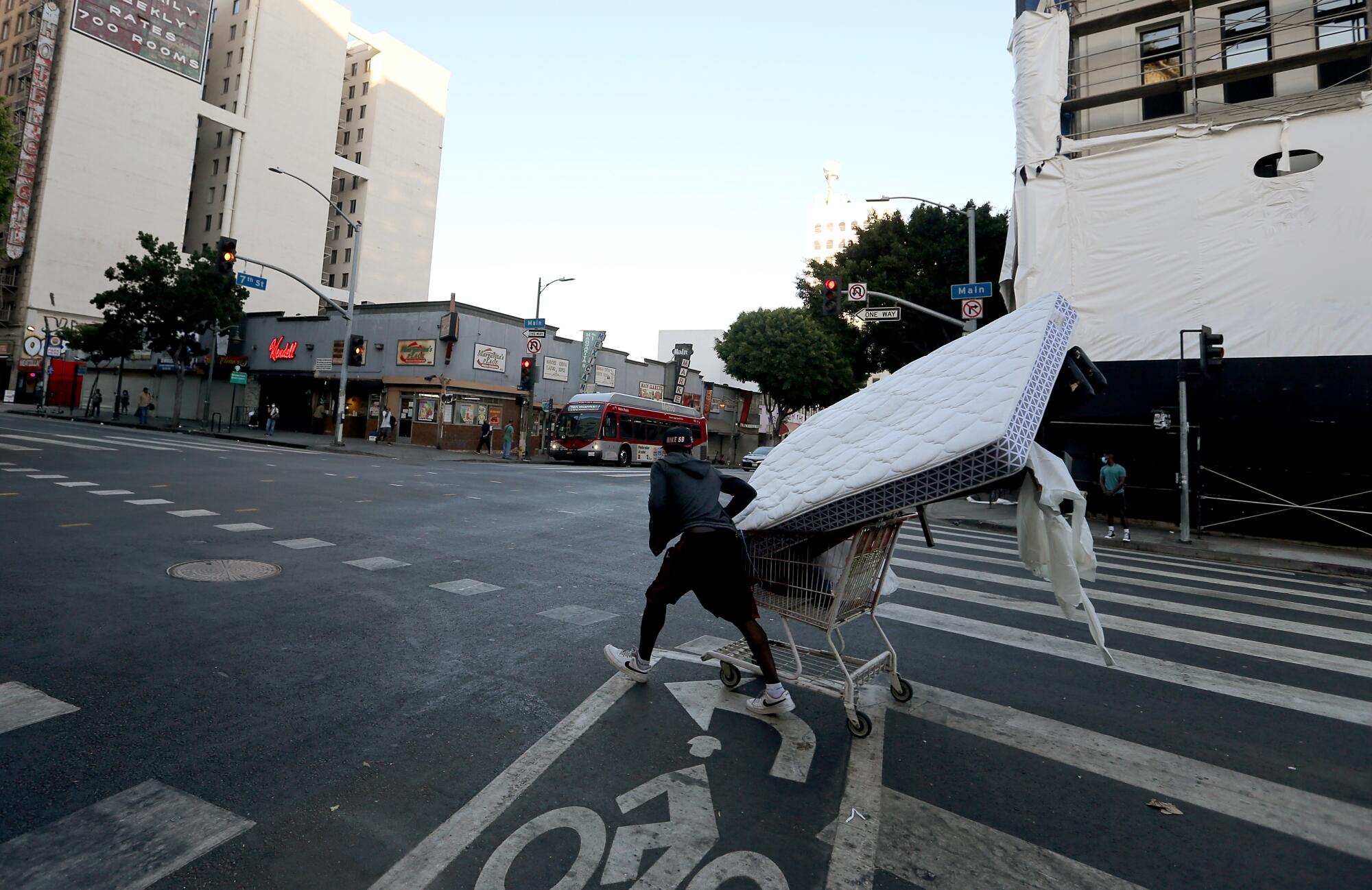 A man uses a shopping cart to transport a mattress up Spring Street in downtown Los Angeles.