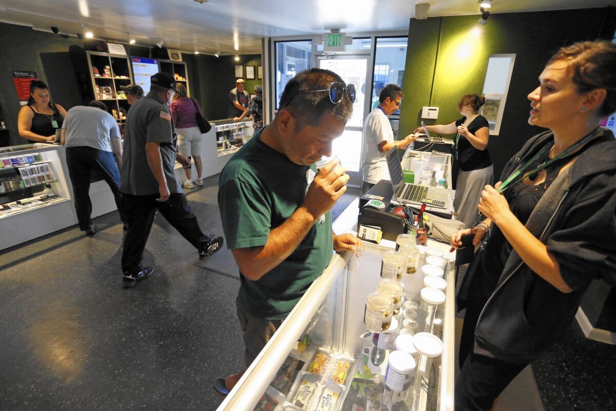 Customers shop at the Grass Station, a marijuana shop in Denver. Because of federal banking regulations barring financial institutions from working with pot sellers, Colorado's $700-million-a-year industry runs almost entirely on cash.
