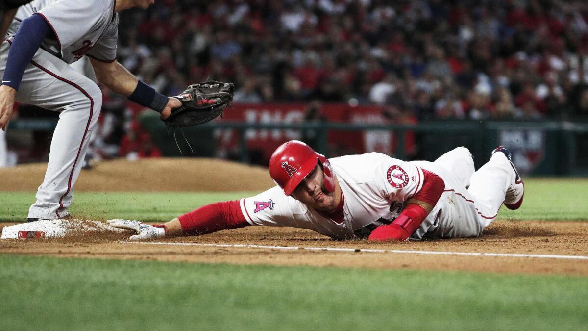 Mike Trout dives back to first base safely on a pick off attempt against Minnesota Twins first baseman Joe Mauer in the fifth inning.