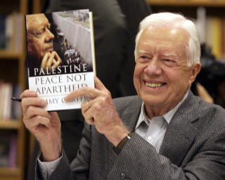 Former President Carter holds a copy of his book "Palestine: Peace, Not Apartheid" in 2006.